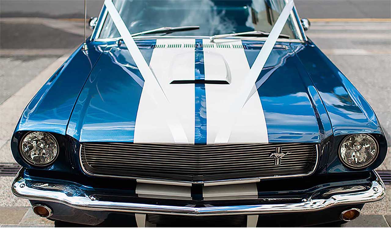 Blue Shelby 1965 Mustang Fastback front view with white wedding ribbons