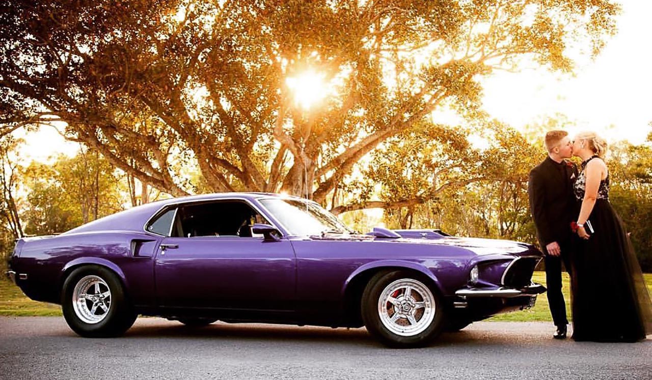 Side view Red Mustang coupe with young man in formal attire